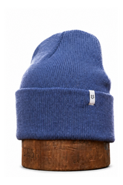 A blue ribbed knit beanie hat displayed upright on a round wooden block against a plain white background.