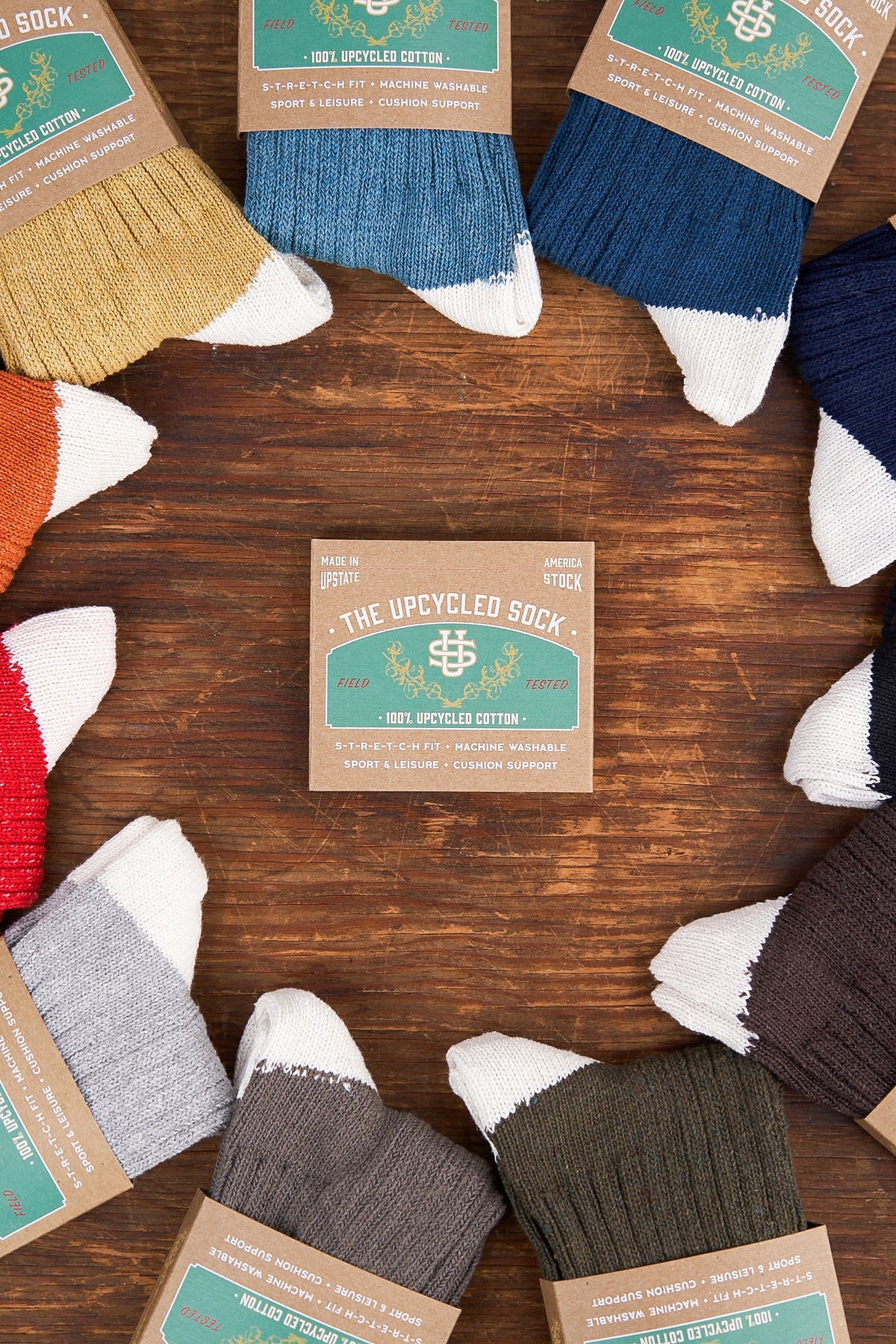 Collection of upcycled socks on a wooden surface with branded packaging.
