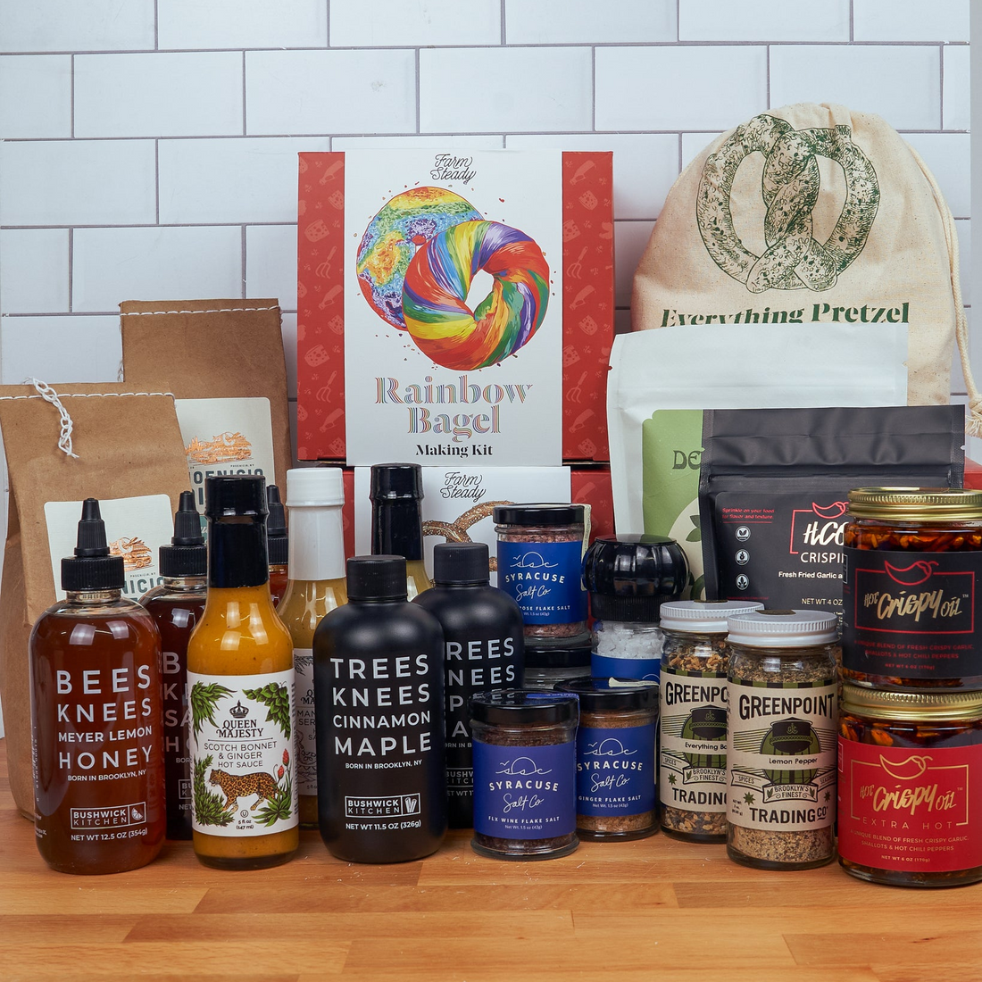 Assorted food products including bottles, jars, and a bag on a wooden surface with a tiled wall background.
