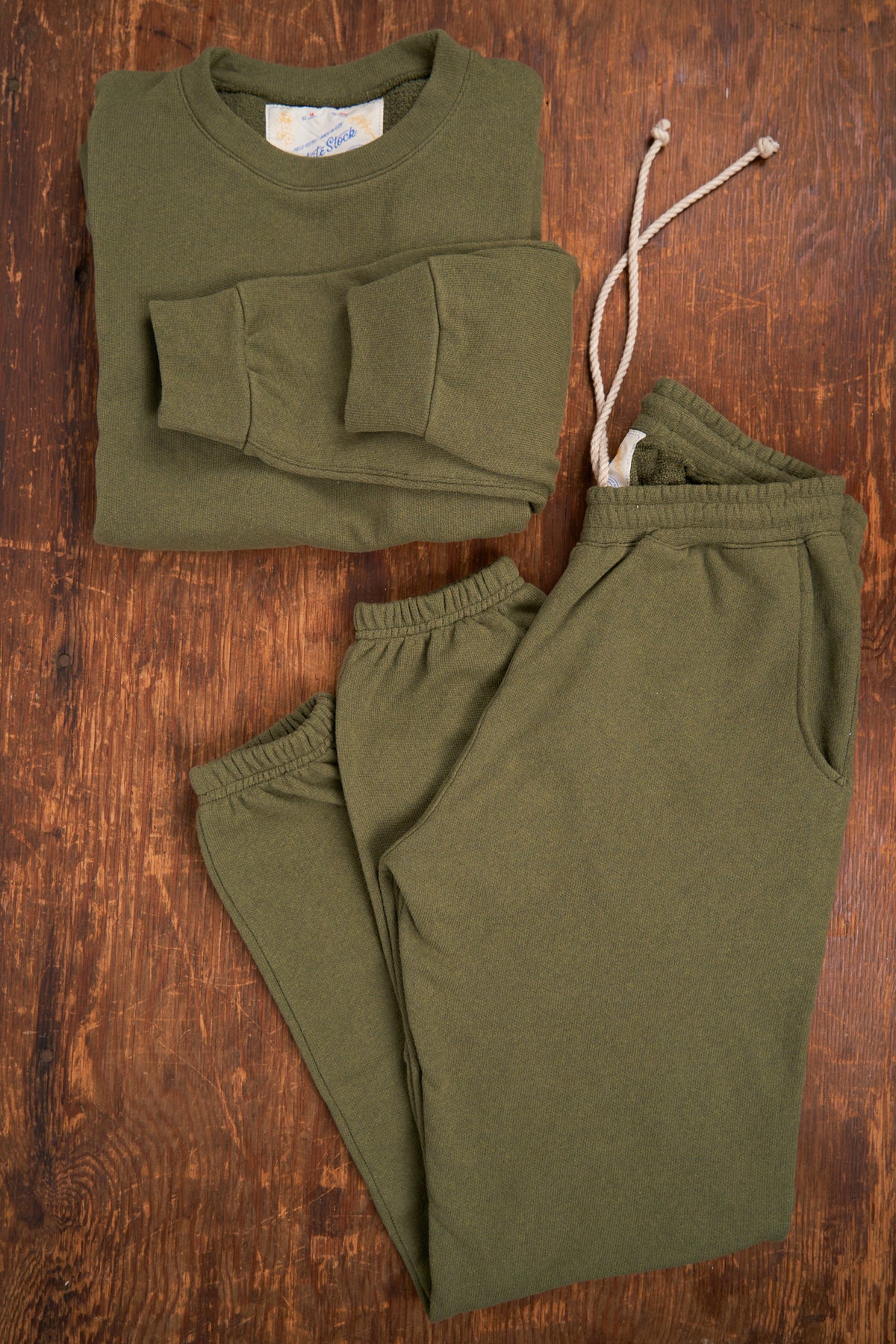 Green sweatshirt and pants set on a wooden surface