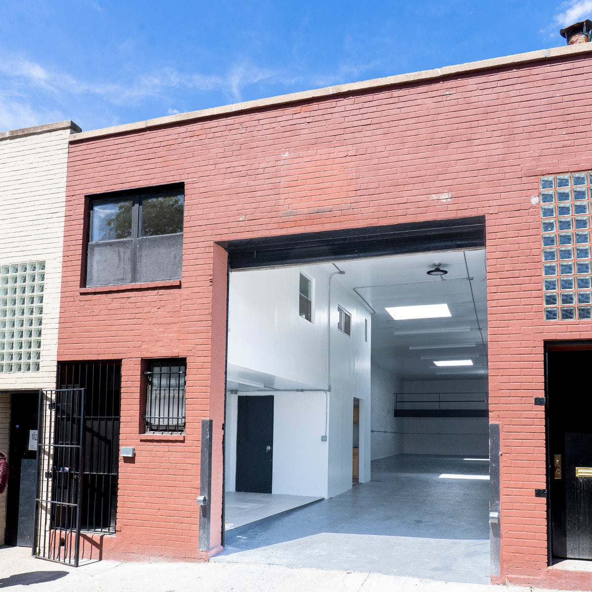Modern building with a large open garage door under a clear blue sky.