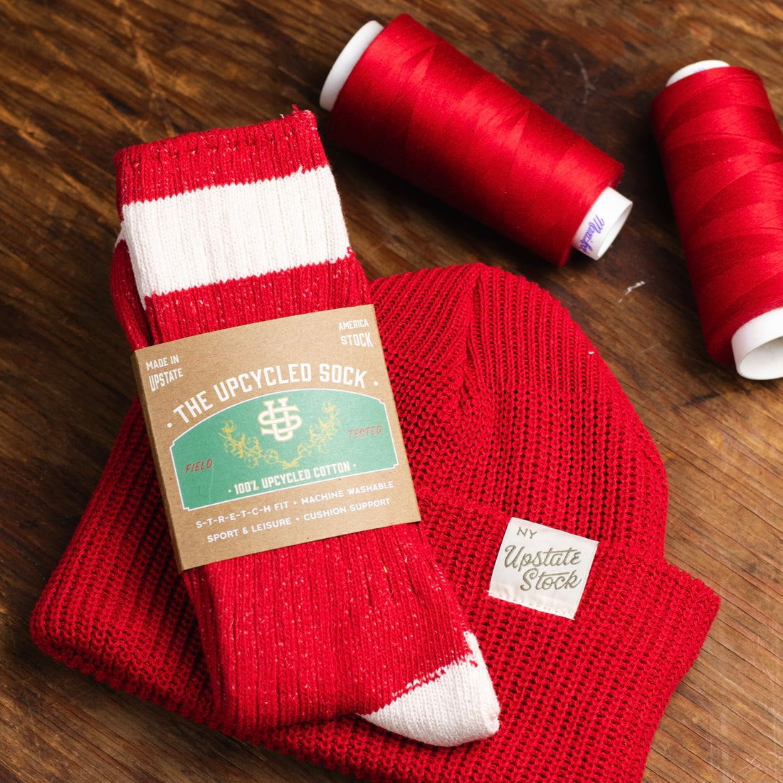 Close up of a red upcylced sock, beanie and thread.